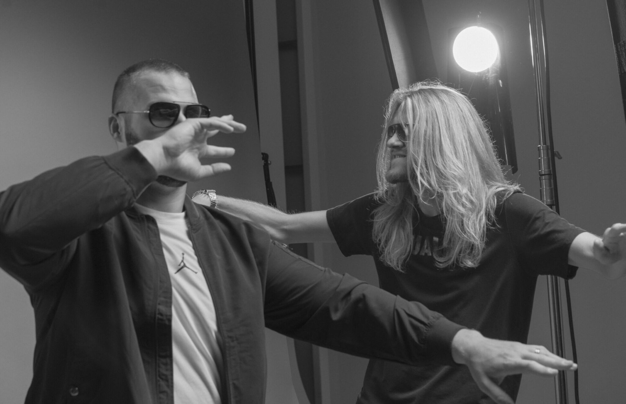 Zwei Männer posieren locker im Fotostudio mit Beleuchtung, einer mit Sonnenbrille, humorvolle Szene
